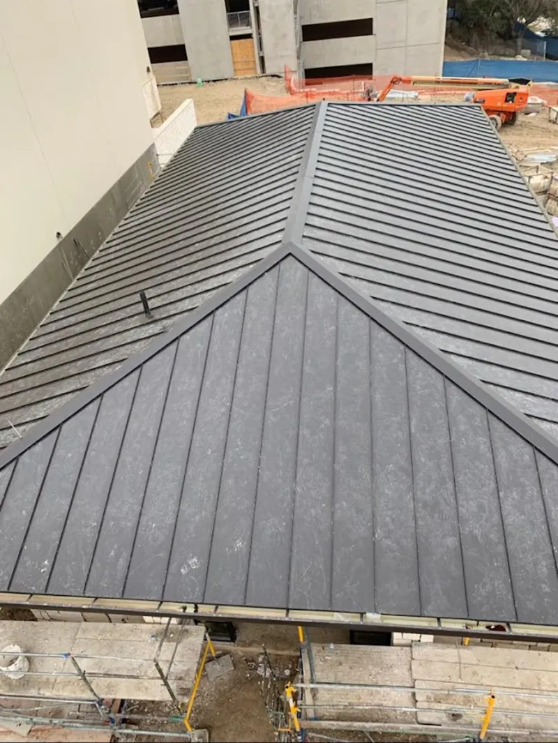Commercial metal roof construction with crane equipment in Cumming